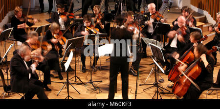 Orchester spielen mit einem Dirigenten, verschwommenes mit Geschwindigkeit der Bewegung. Stockfoto