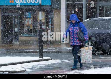 Ilkley, West Yorkshire. 27 Feb, 2018. UK Wetter: eine Frau in Ilkley, Kopf gesenkt, im Winter Kleidung mit Haube und Handschuhe & Stiefel angezogen, ist die fallende Schnee, während Sie an Geschäften in der Brook Street trotzen. 27. Februar 2018, Skipton, Großbritannien Quelle: Ian Lamond/Alamy leben Nachrichten Stockfoto