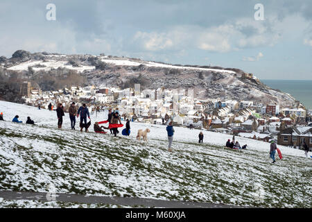 Hastings, Winter, East Sussex, Großbritannien, 27. Februar 2018. Familien haben Spaß im Schnee auf West Hill, mit Hastings Altstadt im Tal und dem schneebedeckten East Hill dahinter. Stockfoto