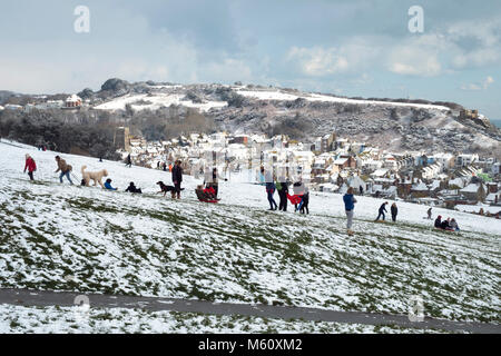 Hastings, Winter, East Sussex, Großbritannien, 27. Februar 2018. Familien haben Spaß im Schnee auf West Hill, mit Hastings Altstadt im Tal und dem schneebedeckten East Hill dahinter. Stockfoto