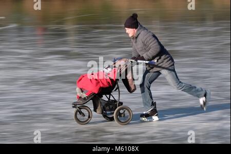 27 Februar 2018, Deutschland, Leipzig: Ein junger Vater Schlittschuhlaufen auf dem See in der Clara Zetkin-Park eingefroren. Es gibt Frost in Deutschland bis zum Wochenende. Foto: Sebastian Willnow/dpa-Zentralbild/dpa Stockfoto