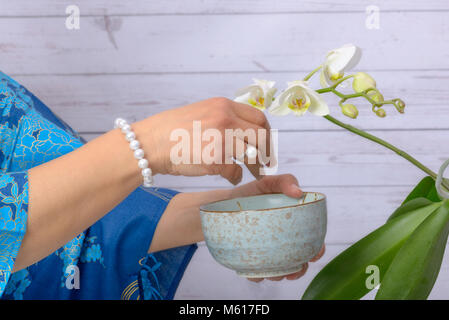 Frau kümmert sich um die weiße Orchidee, das Tragen von Ring und Armband der Japanischen weißen Perlen. Stockfoto