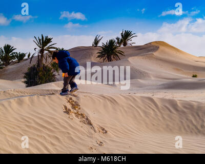 Kind in der Sahara spielt mit dem Sand der Dünen, touristische Urlaub Douz Tunesien Stockfoto