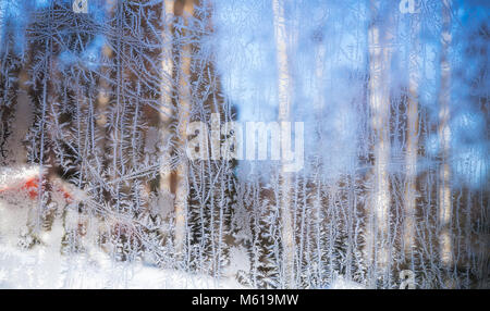 Fenster Frost. Eiskristalle Muster auf frozen Glas mit unscharfen ländliche Landschaft Hintergrund Stockfoto