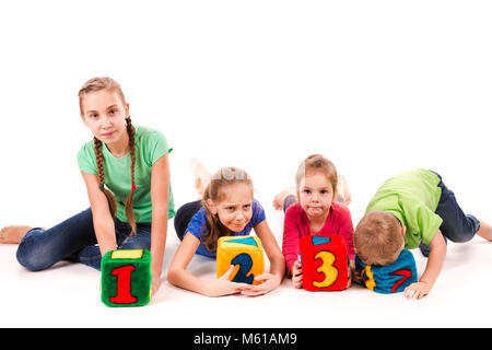 Happy Kids holding Bausteine mit Zahlen auf weißem Hintergrund. Teamwork Konzept. Stockfoto