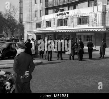 Ein Cordon der Polizei stand Guard wie Dr. Hendrik Verwoerd, der Südafrikanische Premierminister, kommt mit seiner Frau Betsie im Dorchester Hotel in London. Die Verwoerds' Ankunft war b Die Mitglieder der British National Party vor dem Hotel angefeuert. Stockfoto