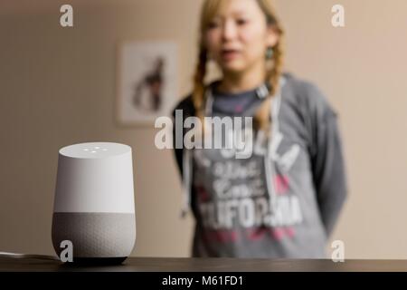 Frau im Gespräch mit Google Home smart-Sprecher in einem Wohnzimmer in Kalifornien, im Februar 2018. | Verwendung weltweit Stockfoto