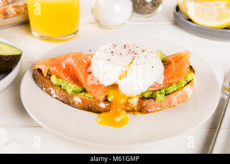 Gesundes Frühstück mit Vollkornbrot Toast, zertrümmerte, Avocado, Lachs und pochiertem Ei Stockfoto
