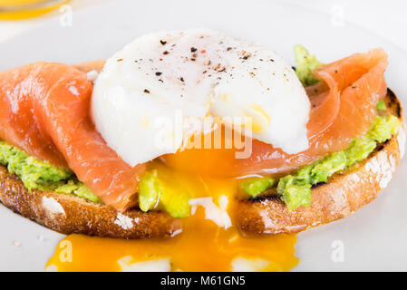 Gesundes Frühstück mit Vollkornbrot Toast, zertrümmerte, Avocado, Lachs und pochiertem Ei Stockfoto