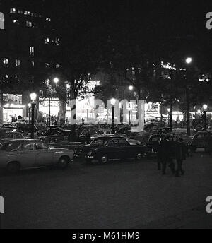 1950, Paris, Frankreich, historische Bild der Stadt bei eveningtime wih Autos der Ära neben dem berühmten Boulevard geparkt, Avenue des Champs Elysees. Durch die Bäume können die berühmten Normandie Kino an 116 Champs Eylsees gesehen werden. Stockfoto