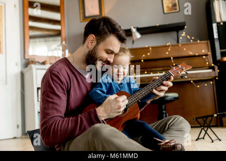 Vater lehre Tochter Gitarre im Zimmer zu Hause zu spielen Stockfoto