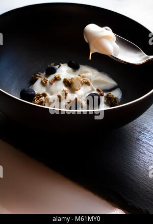 Frühstück mit frischen Blaubeeren, Raps und Joghurt im Schlag Schüssel auf Stein Schiefer Stockfoto