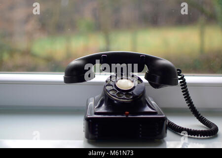 Vintage schwarz Telefon auf dem Tisch in der Nähe der Fenster mit verschwommenen Hintergrund. Stockfoto