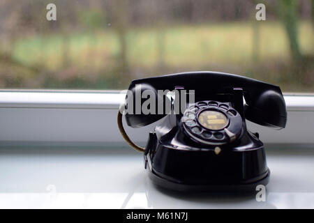 Vintage schwarz Telefon auf dem Tisch in der Nähe der Fenster mit verschwommenen Hintergrund. Stockfoto