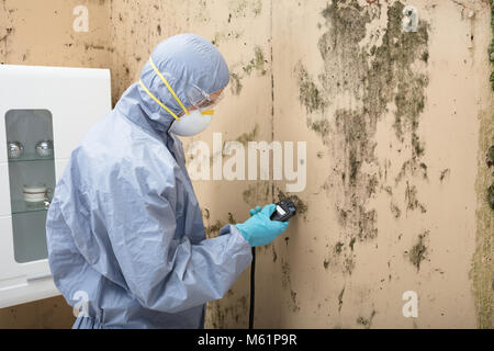 Junge männliche Techniker in Uniform Installation TV Satellitenschüssel auf Wand Stockfoto