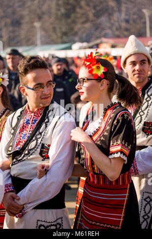 PERNIK, Bulgarien - 26. JANUAR 2018: Paar der Tänzer in der bulgarischen Folklore Kostüme halten und jedes andere an der sonnigen jährliche Internationale Festi suchen Stockfoto