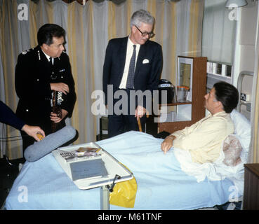 British Home Secretary Douglas Hurd, verletzten Polizisten im Krankenhaus nach der Tottenham Unruhen auf Broadwater Farm Estate in 1985. Auf der linken Seite ist stellvertretender Leiter des Metropolitan Peter Imbert, der später Baron Imbert. Stockfoto