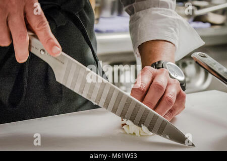 Damit Sie keine Lust auf Weinen haben, hier ein Tipp des sous Chefs: Atmen Sie beim Schälen und Zerkleinern von Zwiebeln durch den Mund. Ein scharfes Messer ist ebenfalls sehr wichtig - zum Beispiel das Chroma P 30 im Porsche-Design. Stockfoto