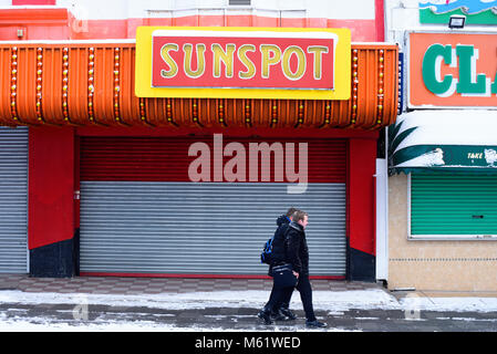 Menschen zu Fuß im Schnee Vergangenheit Sonnenfleck Spielhalle in Southend On Sea, Essex, während das Tier aus dem Osten wetter Phänomen Stockfoto