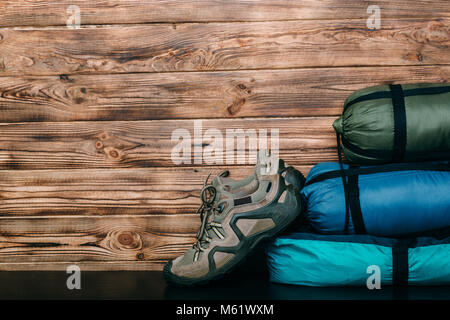 Trekking Schuhe, Schlafsäcke und Zelte auf hölzernen Stockfoto