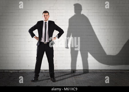 Schatten des Superhelden gebildet, an der Wand hinter der Junge Unternehmer Stockfoto