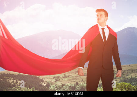Junge zuversichtlich Super Geschäftsmann in rotem Umhang gegen einen malerischen Hintergrund Stockfoto