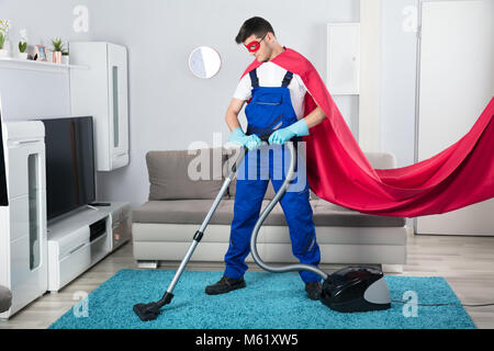 Superhelden Hausmeister Reinigung Teppich mit Staubsauger im Wohnzimmer Stockfoto