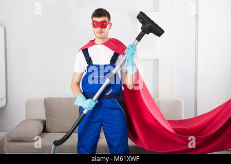 Superhelden Hausmeister mit Staubsauger im Wohnzimmer Stockfoto