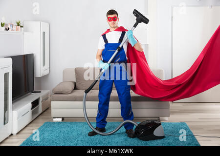 Superhelden Hausmeister Reinigung Teppich mit Staubsauger im Wohnzimmer Stockfoto