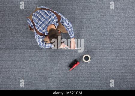Nahaufnahme der Tischler Hand verlegen Teppich mit dem Fräser Stockfoto