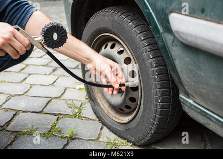 Person's Hand Messen auto Reifendruck mit einem Manometer im Freien Stockfoto