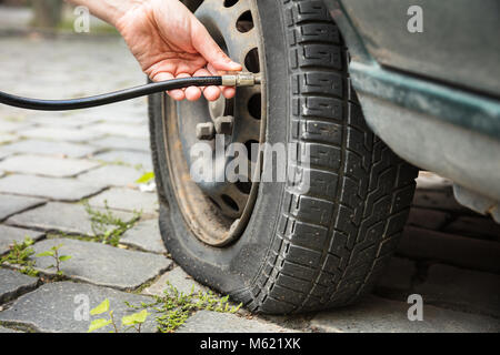 Person's Hand Messen auto Reifendruck mit einem Manometer im Freien Stockfoto