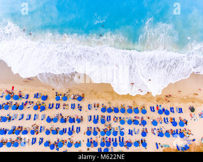 Aus der Vogelperspektive einen Strand mit großen Wellen, Sonnenliegen und Sonnenschirme in Lefkada, Griechenland Stockfoto