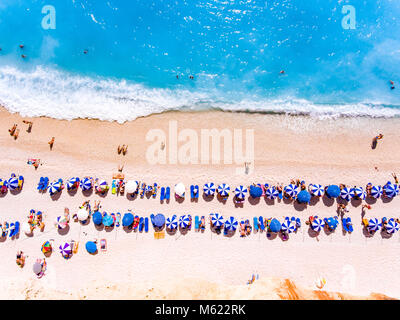 Von oben nach unten Blick auf einen Strand mit Touristen suntbeds und Sonnenschirme mit Sandstrand und das klare blaue Wasser in Griechenland Stockfoto