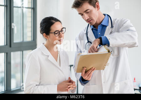 Zwei Ärzte zusammen Kontrolle der Krankenakte eines Patienten Stockfoto