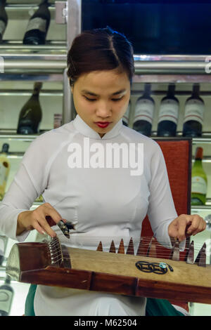 Eine vietnamesische Frau spielt die traditionelle 17-saitige Đàn Tranh Stockfoto