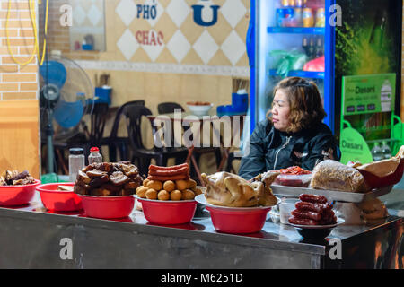 Eine Frau verkauft Huhn, Wurst, Schweine- und anderen Fleischerzeugnissen auf einer Straße in Hanoi, Vietnam. Stockfoto