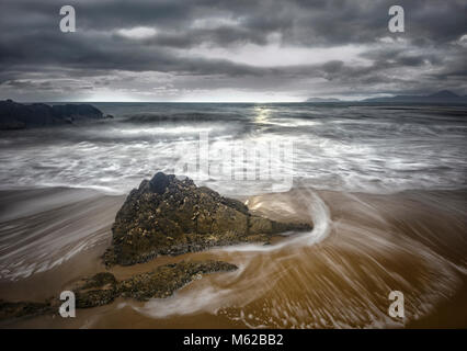 Wellen motion blur um einen Felsen in Yorkeys Knob Beach während eines Sturms, Cairns Northern Beaches, Far North Queensland, FNQ, QLD, Australien Stockfoto