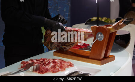 In Scheiben geschnittene Getrocknete chamon Prosciutto. Ein Mann schneidet einen jamon, ein in warmen Farbtönen. Selektiver Fokus. Stockfoto