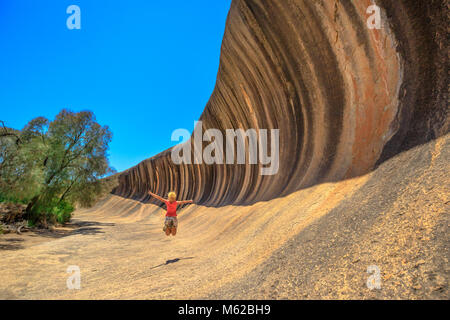 Australische outback in Hyden Wildlife Park. Sorglos kaukasische Frau an der Wave Rock in Hyden, Western Australia springen. Weibliche Brücke in eine natürliche Felsformation in der Form einer Welle. Stockfoto