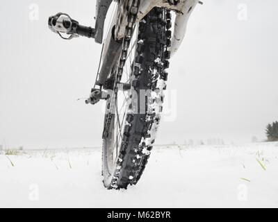 Nahaufnahme der Hinterrad Mountainbike in der verschneiten Wiese in der Landschaft. Detail der Mountainbike. Extreme sportliche Hintergründe. Konzept Stockfoto