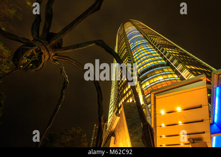 Tokyo, Japan - 20. April 2017: Low Angle View von Mori Tower und Maman Spider Bronze Skulptur in der Nacht in Roppongi Hills Komplex in Minato, Tokio beleuchtet. Nacht Szene. Stockfoto