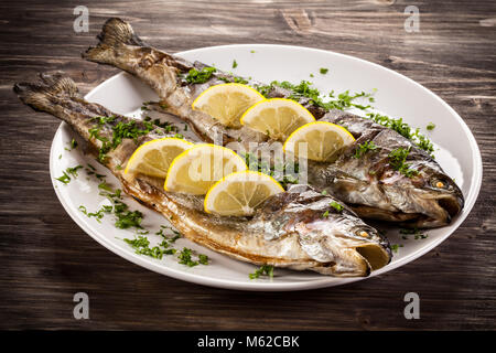 Fischgericht - Gebratenes Fischfilet mit Gemüse auf Holz- Hintergrund Stockfoto