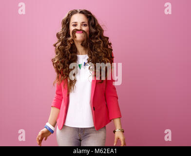 Rosa Stimmung. lächelnd trendy Frau mit langen Welligen brünette Haare auf Rosa, Schnurrbart von Haar isoliert Stockfoto