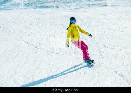 Bild der jungen Frau im Helm reiten Snowboard auf verschneiten Berg Stockfoto