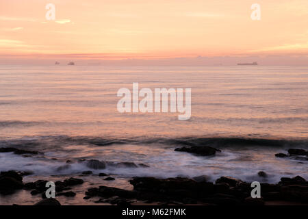 Durban, KwaZulu-Natal, Südafrika, Moody Beach Szene von Schiffen Silhouette am Horizont, die Dämmerung bricht, Umhlanga Rocks Beach, Landschaft Stockfoto