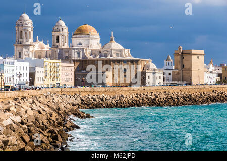 Blick auf Kathedrale von Cádiz (Catedral de Santa Cruz) aus der Ferne, über das Meer, die Küste und die Quay. Andalusien, Spanien Stockfoto