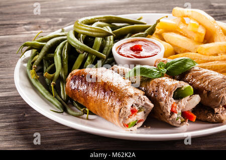 Wickelte Schweinekotelett, Pommes und Gemüse einen hölzernen Tisch Stockfoto