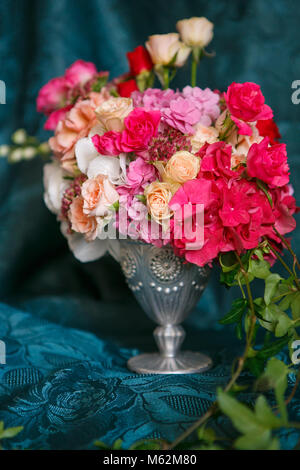 Eine asymmetrische Strauß in eine Vase mit Rosen, Nelken und Hortensien auf dunkelblauem Hintergrund Stockfoto