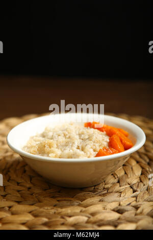 Kalorienarme porridge für eine gesunde Ernährung und Lebensweise. Gerste mit Honig und Bits von orange Kürbis in einem tiefen weiße Platte. Dunkler Hintergrund, Registerkarte Stockfoto